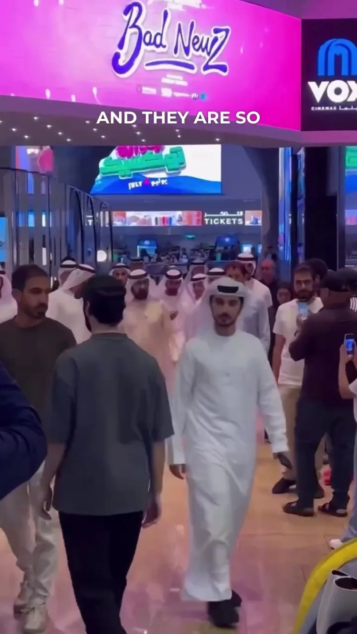 People walking in a modern indoor venue in the UAE, including a man in traditional white robe, suggesting a professional or business setting